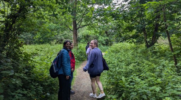 Three walkers smiling into the camera on a treelined path